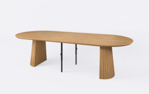 Stół owalny ryflowany na dwóch nogach, rozłożony i poszerzony o dwa dodatkowe wkłady.