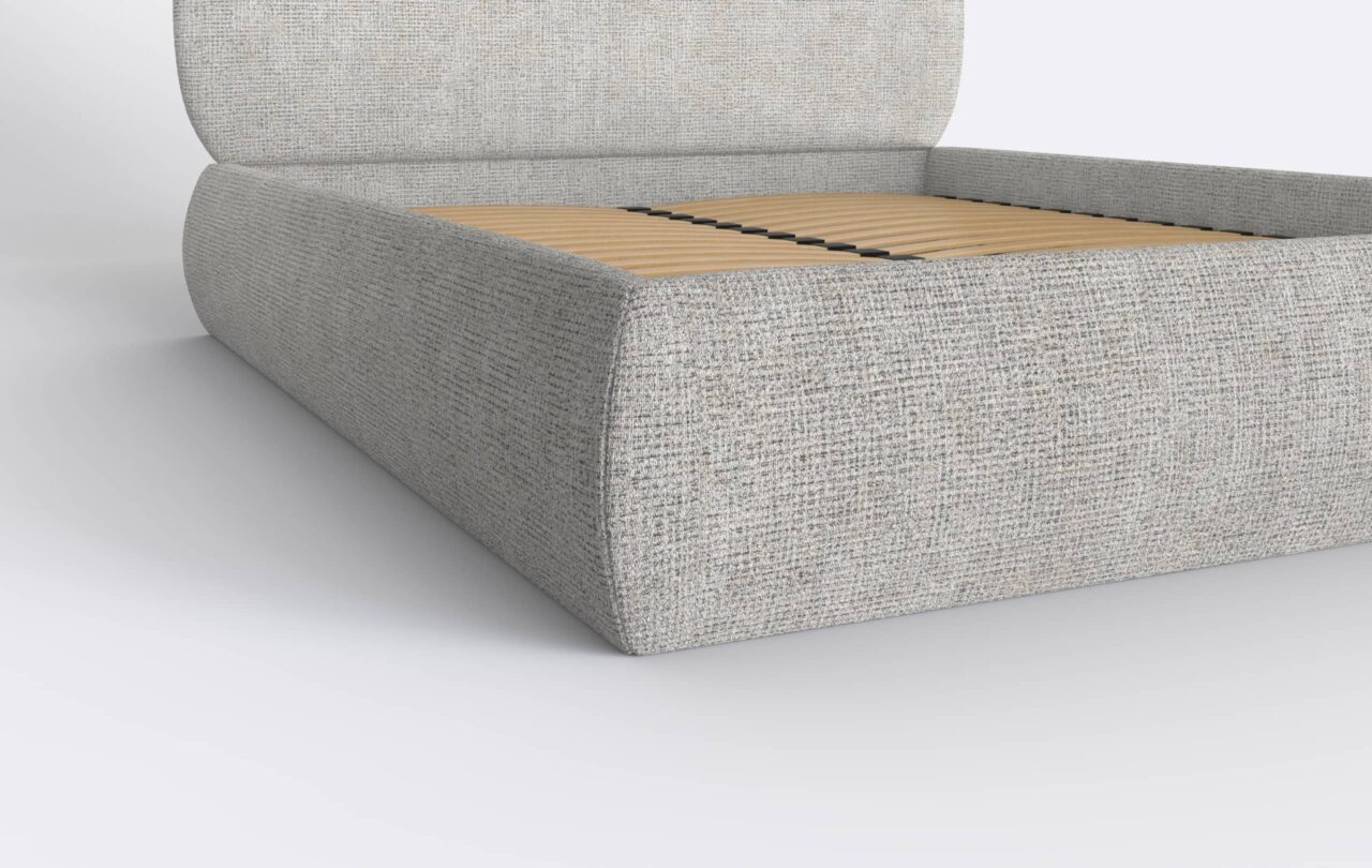 Szare łóżko z zaokrąglonymi bokami, tapicerowane.