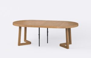 Rozłożony okrągły stół powiększony o dwie wkładki, noga kwadratowa o grubości sześciu centymetrów, o jasnym kolorze.