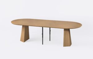 Rozłożony stół owalny, poszerzony o dwie wkładki, w stylu nowoczesnym, o minimalistycznym designie i jasnym kolorze.