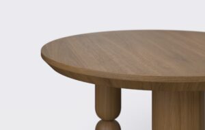 Nowoczesny okrągły stolik z podciętym blatem, wykonany z forniru dębowego.