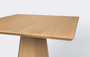 Stół z kwadratowym blatem i krawędzi podciętej od dołu, o jasnym wybarwieniu.