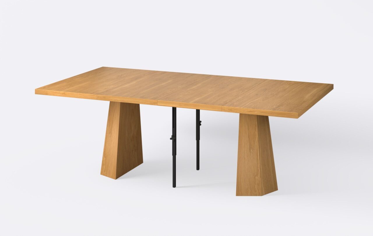 Kwadratowy rozłożony stół z dwoma wkładkami, fornirowany, o ciepłym jasnym wybarwieniu, na jednej nodze.